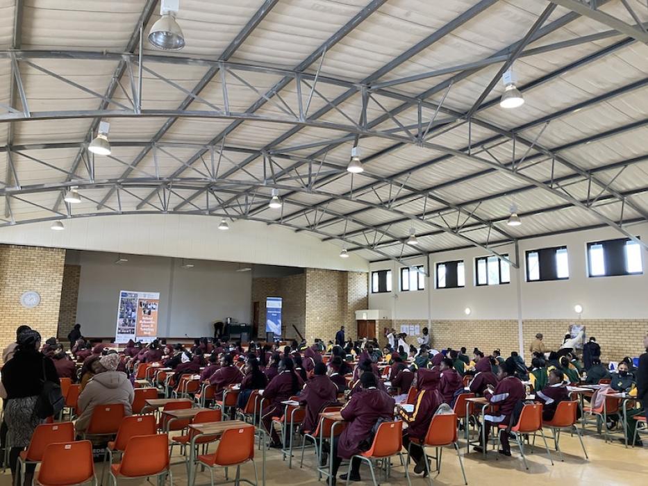 Large hall filled with female learners, teachers and exhibitors