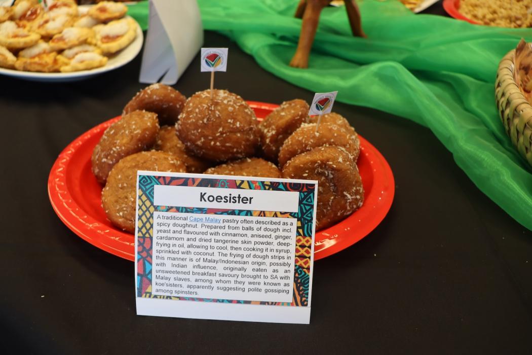Light brown oval shaped donuts with coconut flakes over them on a red plate on a table