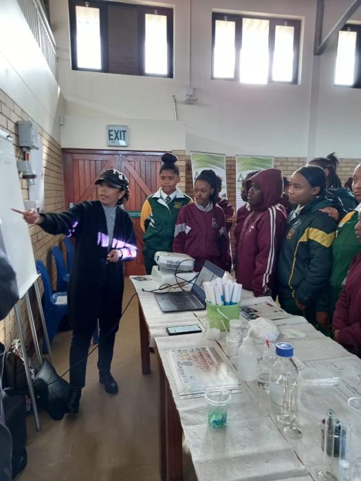 Chemistry Lecturer presenting to young learners around a table
