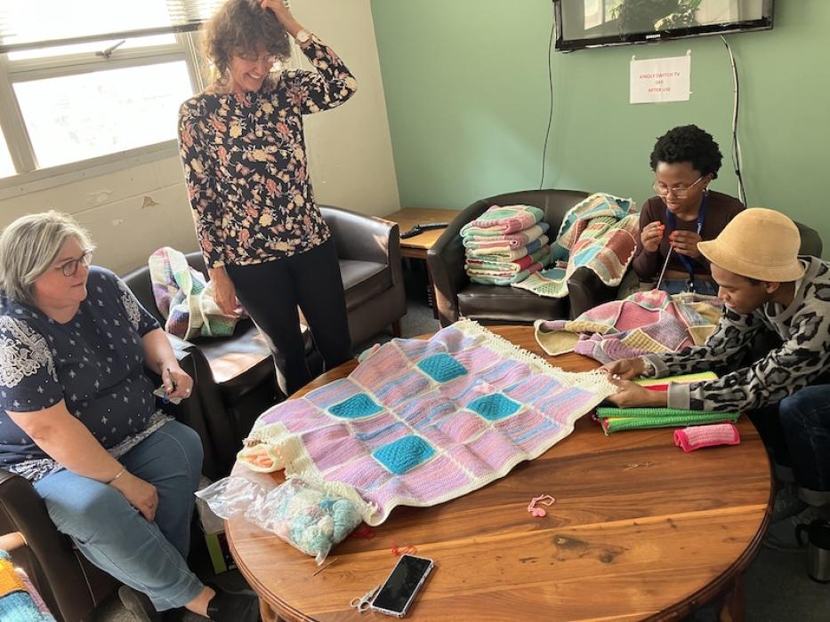 Group of ladies over looking a knitted blanket