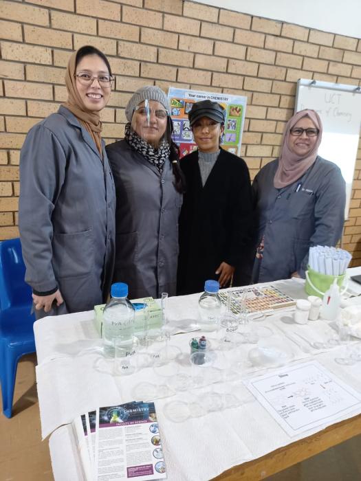 Four chemists posing in front of National Science Week 2023 exhibition table
