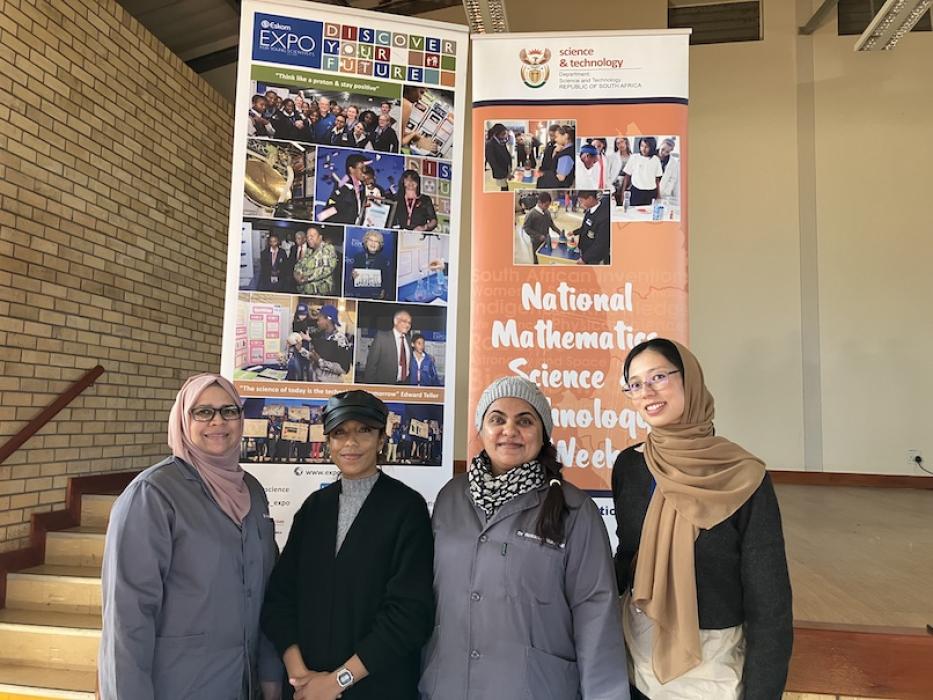 Four chemists posing in front of National Science Week 2023 poster