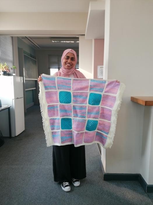 A postgraduate student holding up her knitting