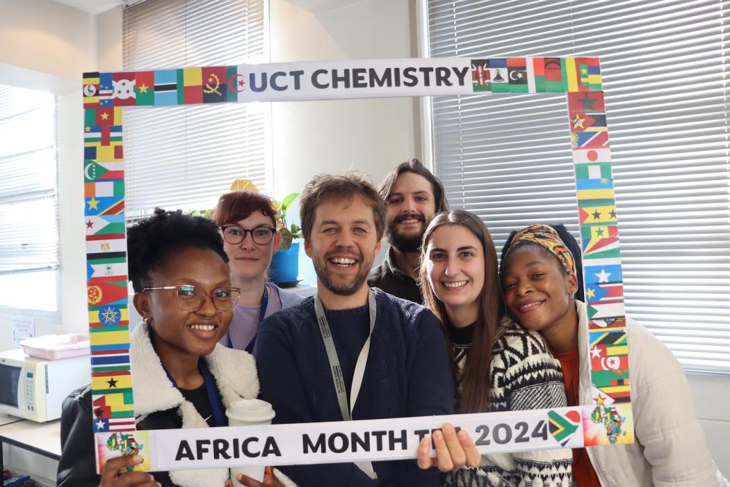 Postgraduate Students and Staff posing with the UCT Chemistry Africa Month Tea 2024 Banner
