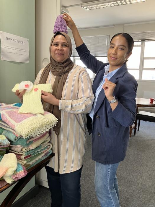 Woman playfully holds a knitted beanie over her colleague's head