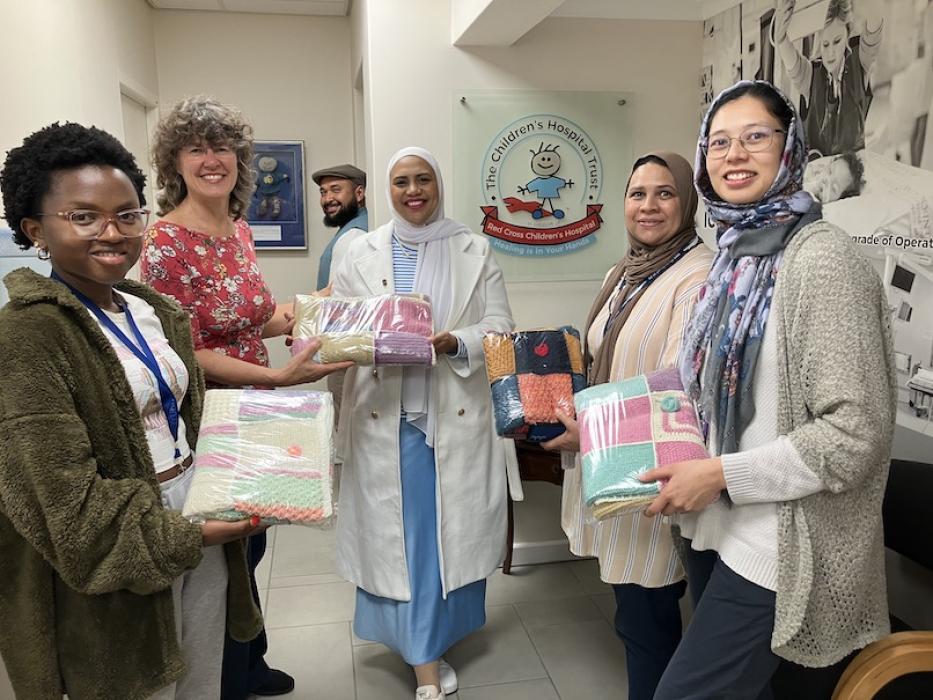 Woman hands parcel over to a representative while her colleagues look on