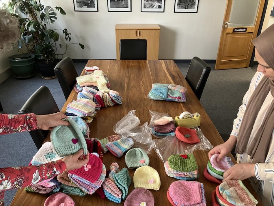 A woman packing knitted beanies neatly into a packet