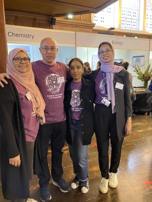 Four chemistry department staff members pose in front of the chemistry exhibition.