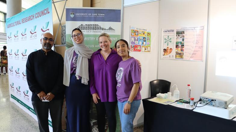A group of people posing for a photo in front of a chemistry poster