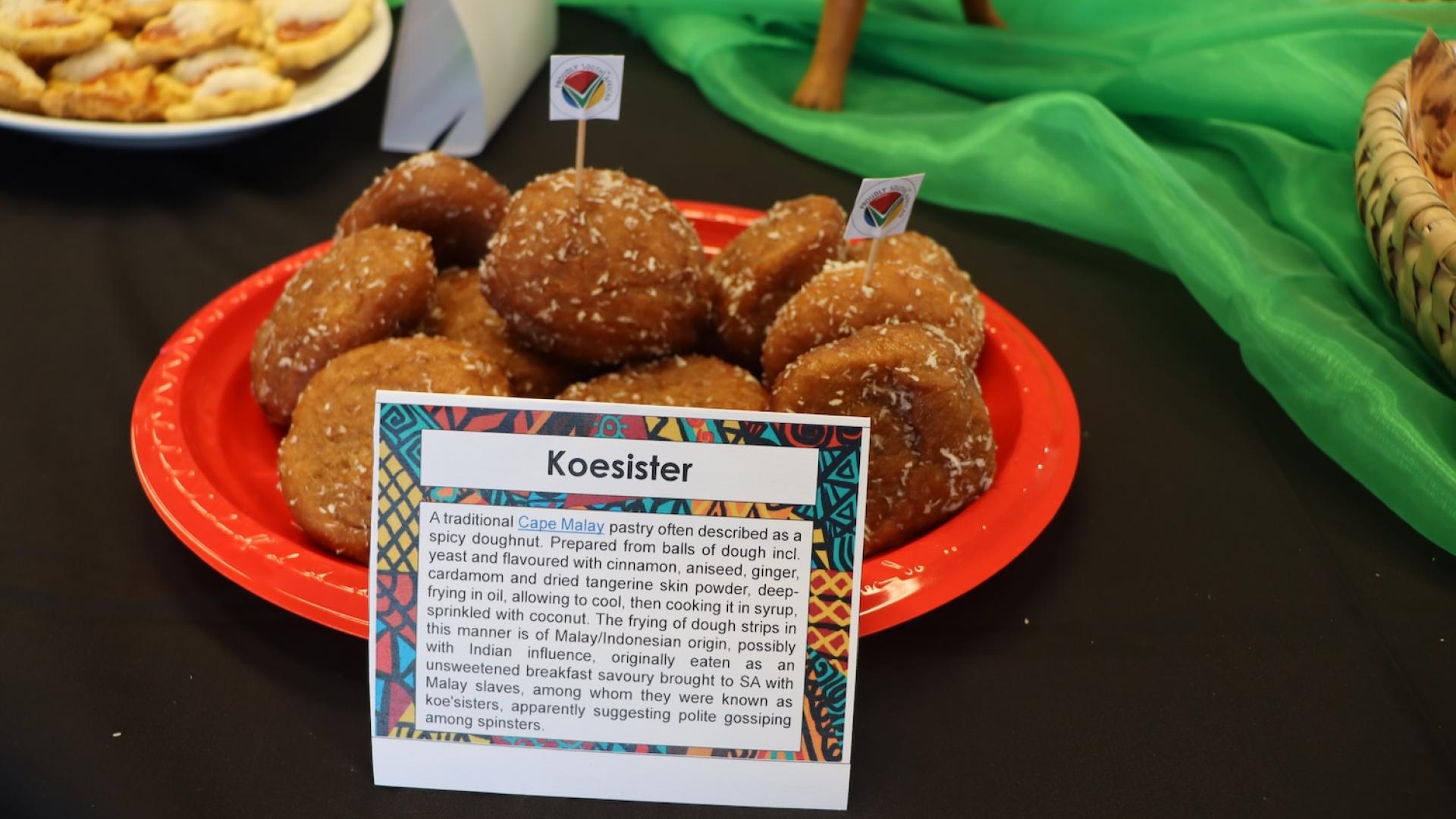 Light brown oval shaped donuts with coconut flakes over them on a red plate on a table