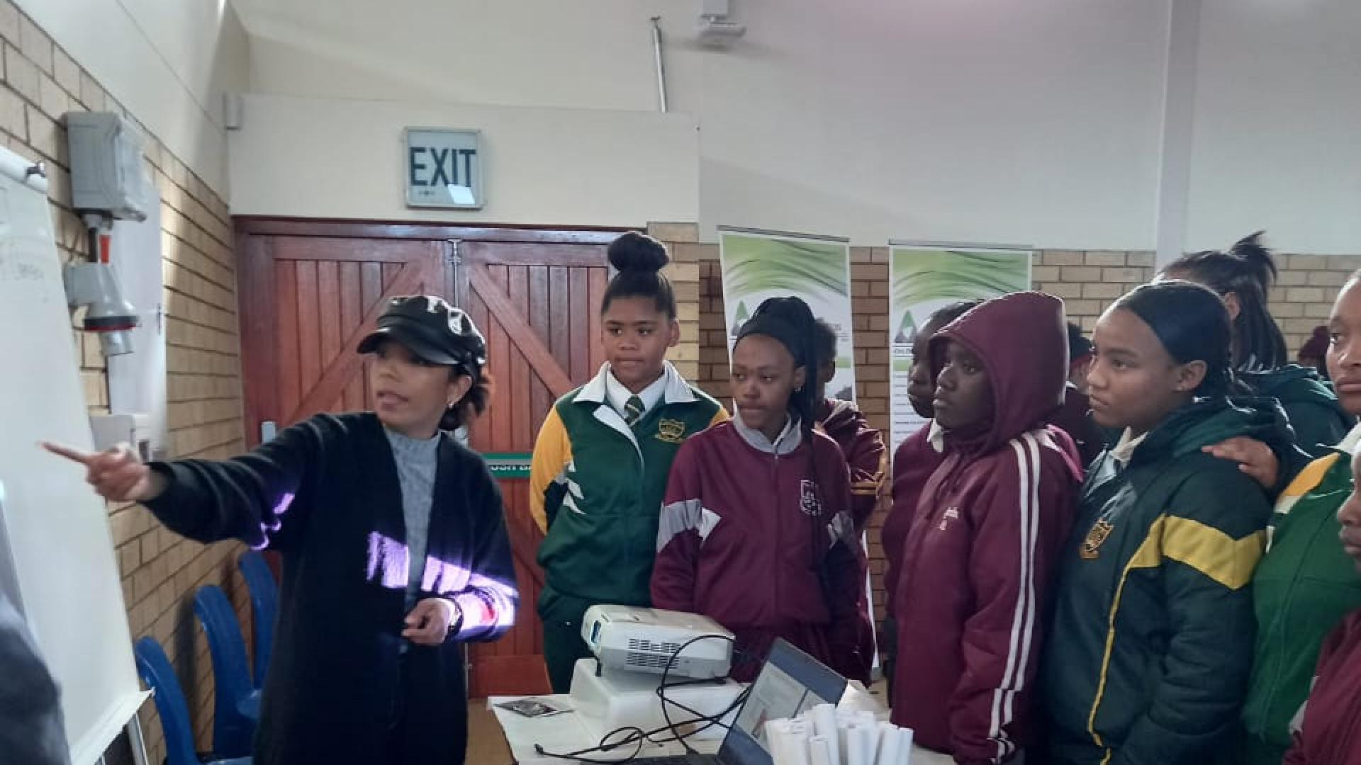 Chemistry Lecturer presenting to young learners around a table