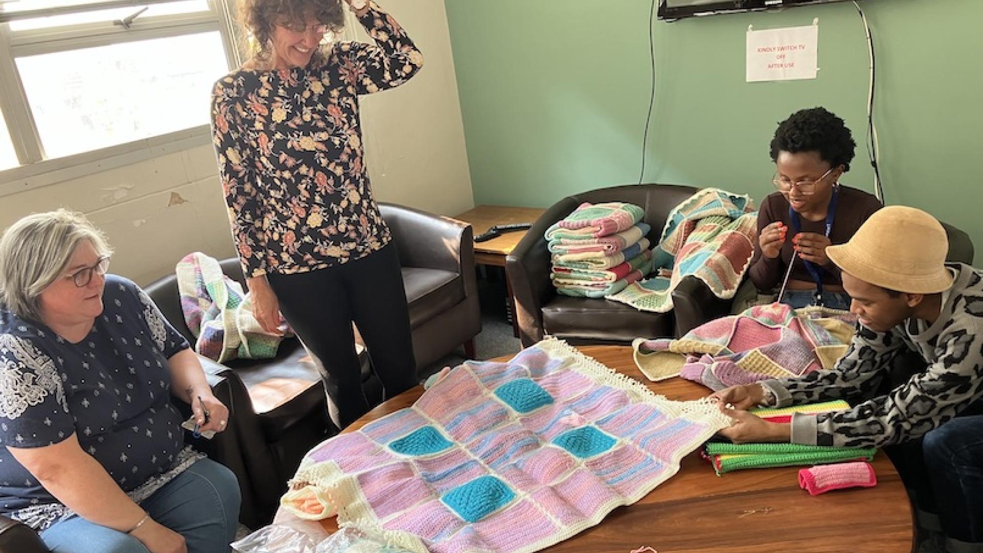 Group of ladies over looking a knitted blanket