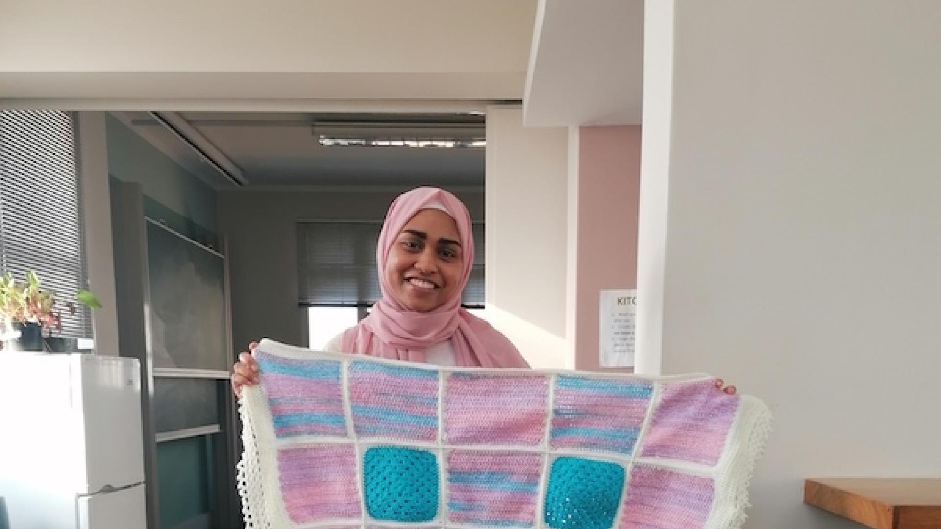 A postgraduate student holding up her knitting