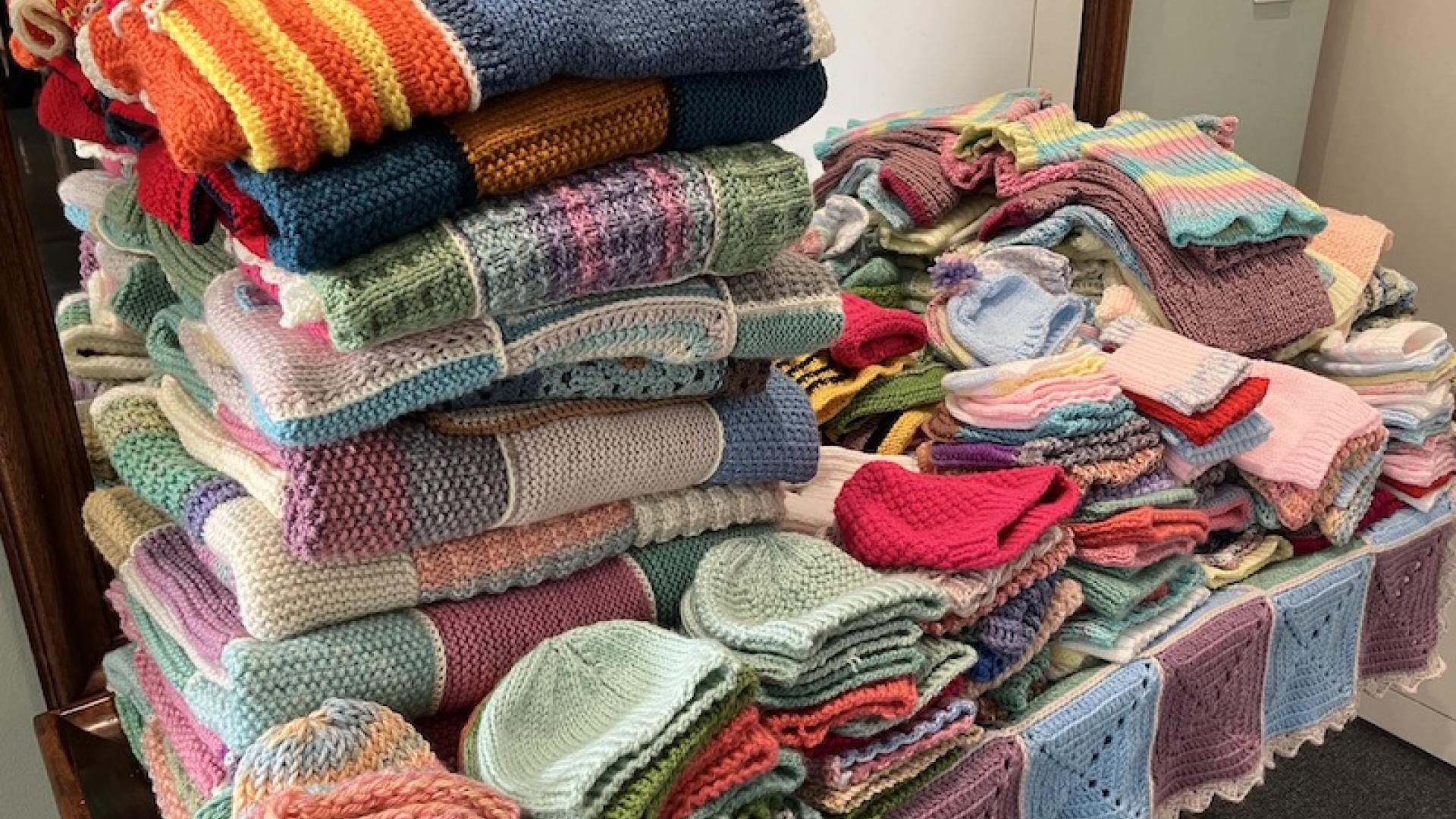 growing pile of knitted and crocheted folded items 