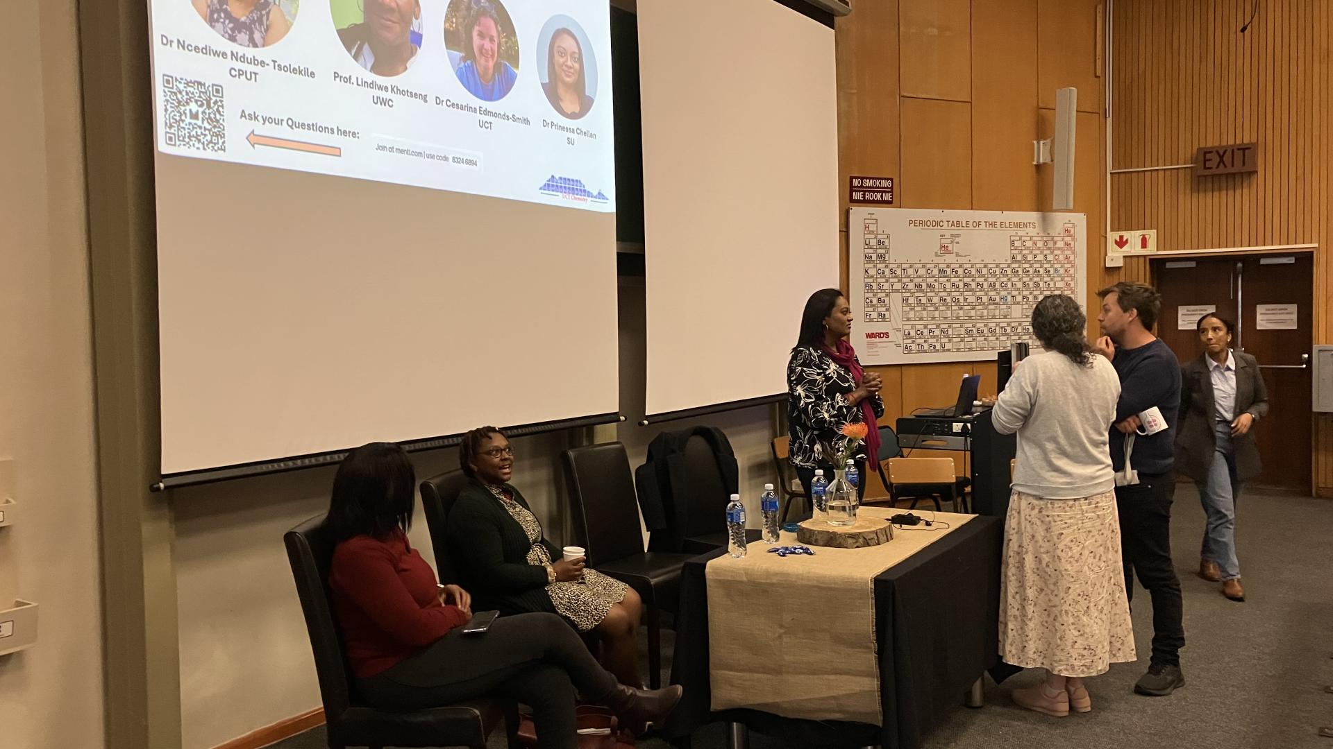 Panel discussion at a chemistry event with audience members and a whiteboard with notes.