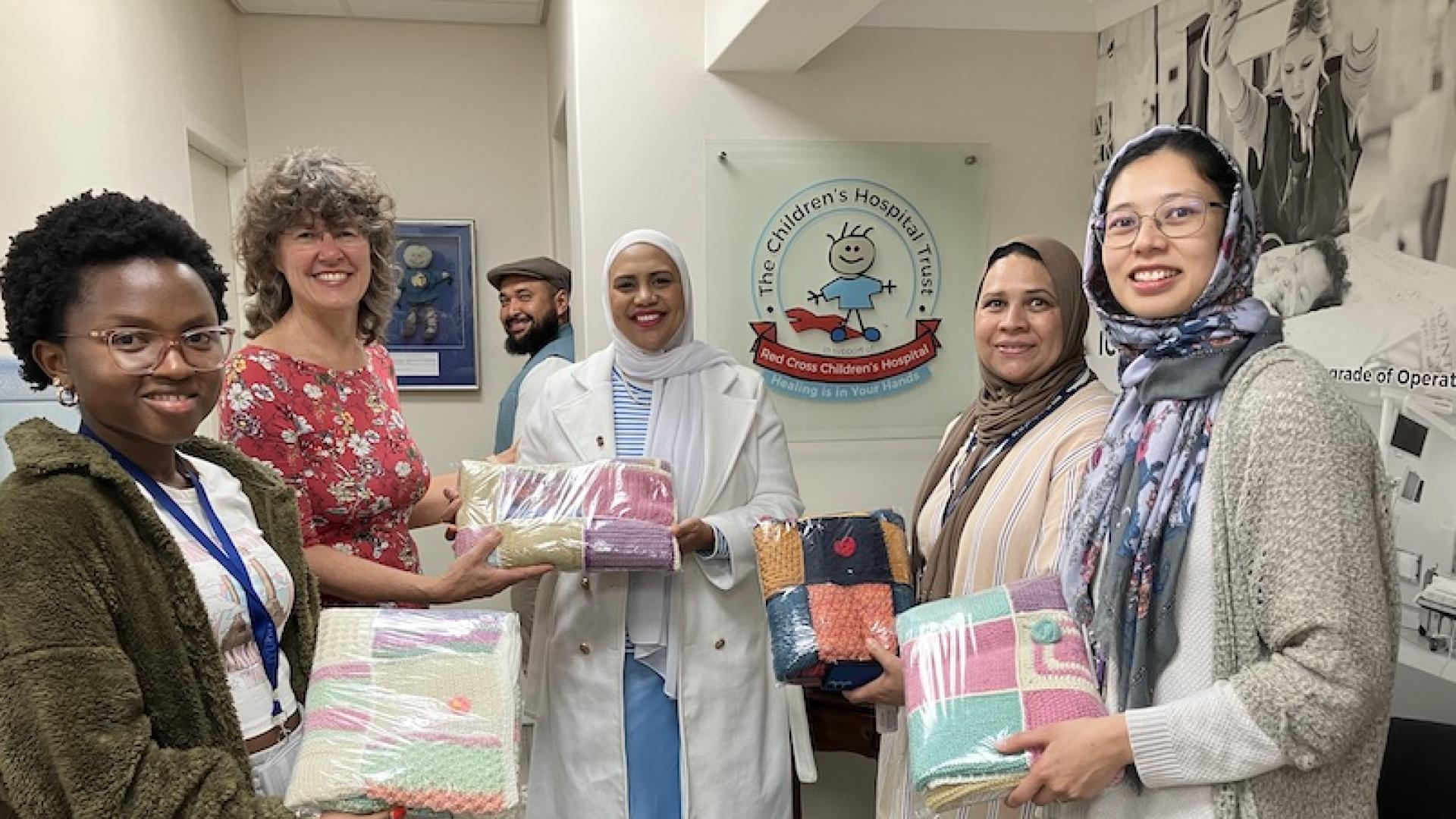 Woman hands parcel over to a representative while her colleagues look on