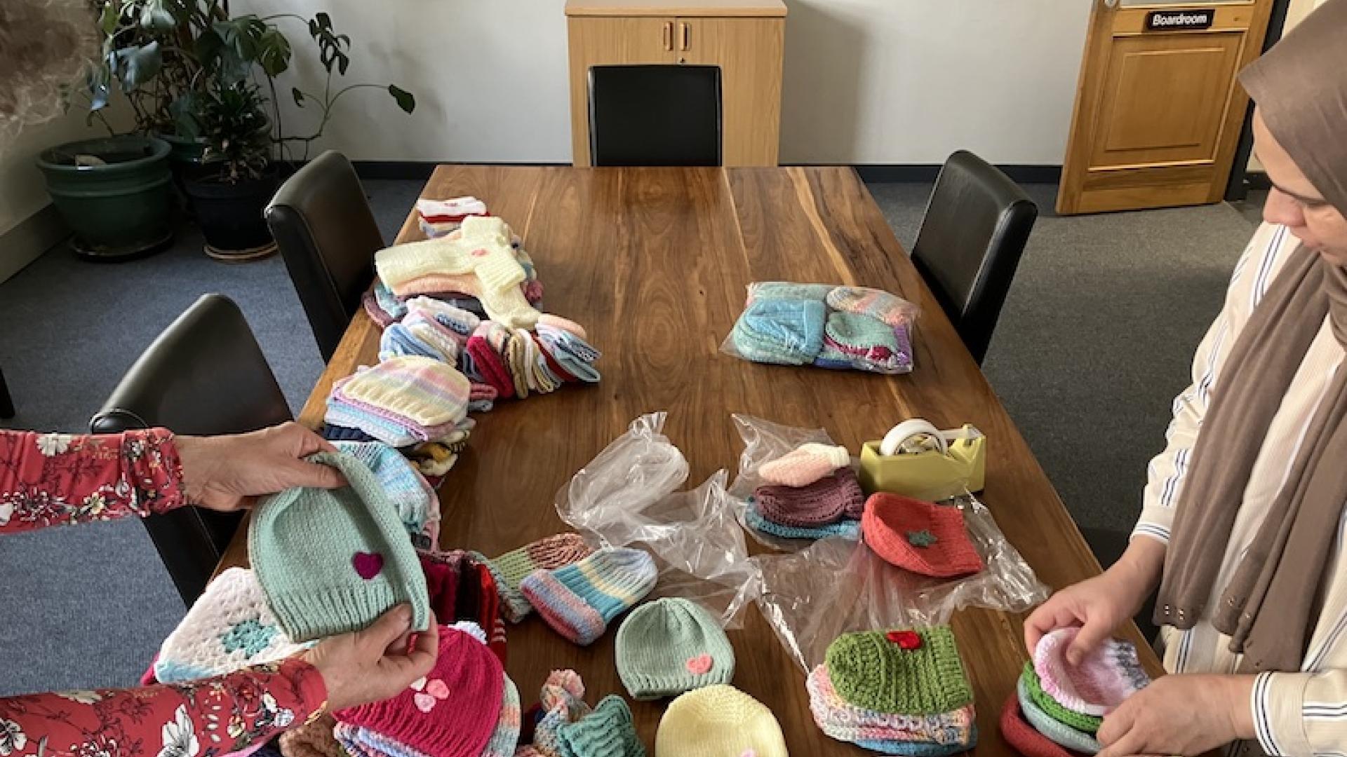 A woman packing knitted beanies neatly into a packet