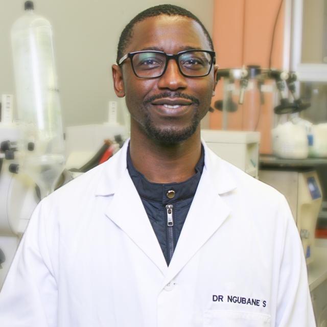 Dr Ngubane smiling in a white lab coat in his laboratory