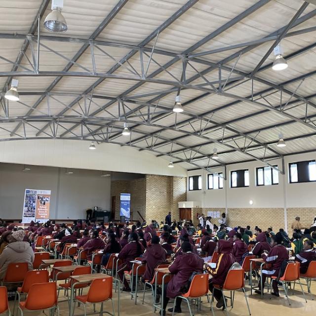 Large hall filled with female learners, teachers and exhibitors