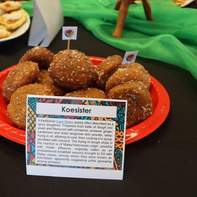 Light brown oval shaped donuts with coconut flakes over them on a red plate on a table