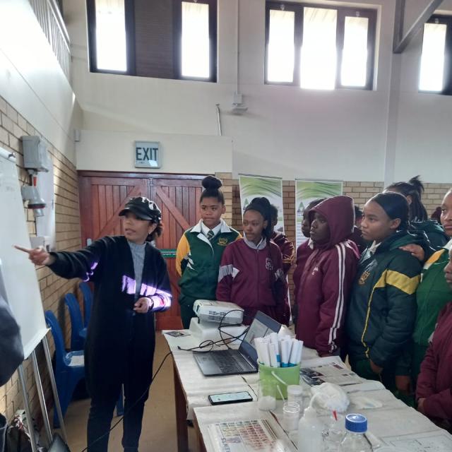 Chemistry Lecturer presenting to young learners around a table