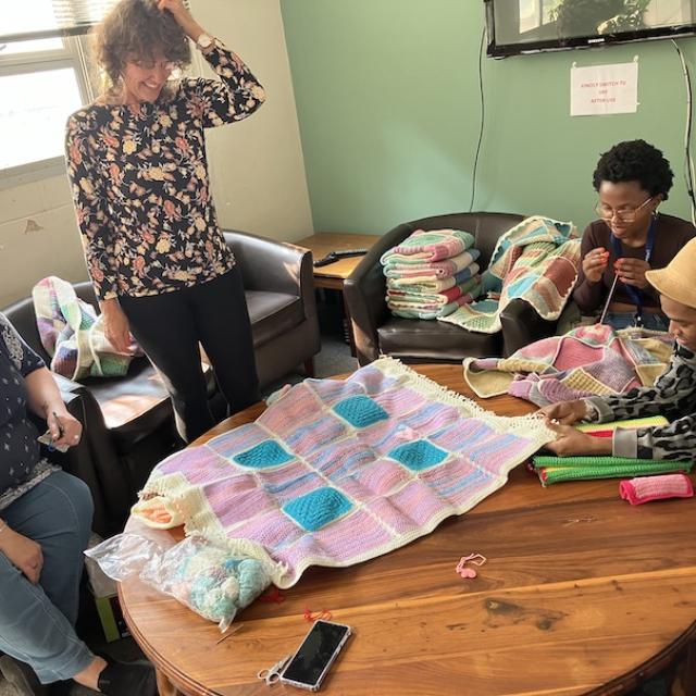 Group of ladies over looking a knitted blanket
