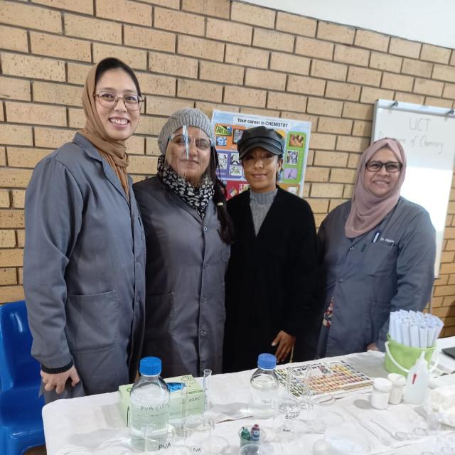 Four chemists posing in front of National Science Week 2023 exhibition table