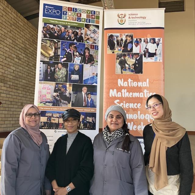 Four chemists posing in front of National Science Week 2023 poster