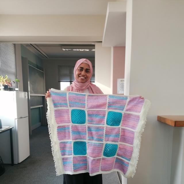 A postgraduate student holding up her knitting