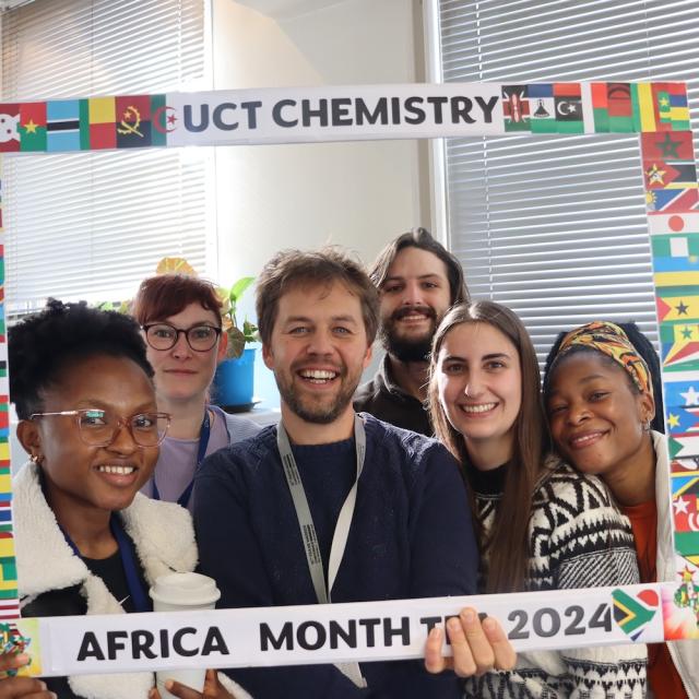 Postgraduate Students and Staff posing with the UCT Chemistry Africa Month Tea 2024 Banner
