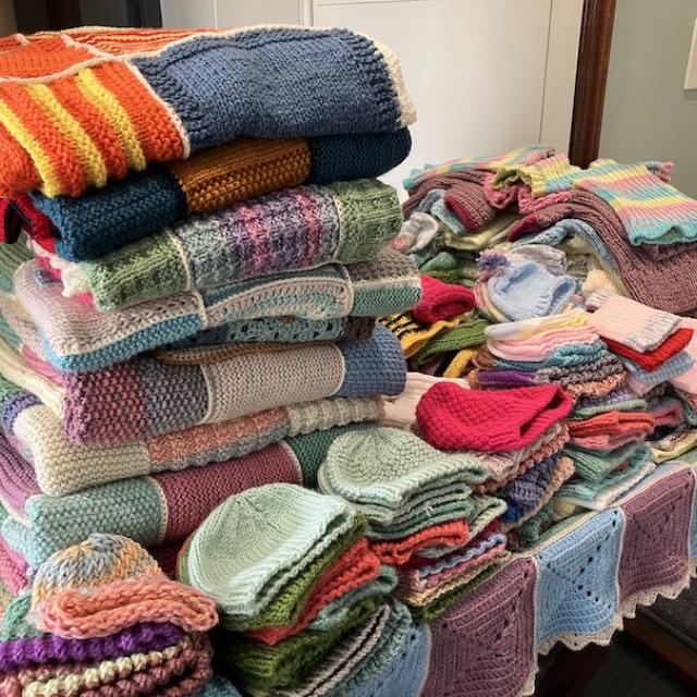 growing pile of knitted and crocheted folded items 