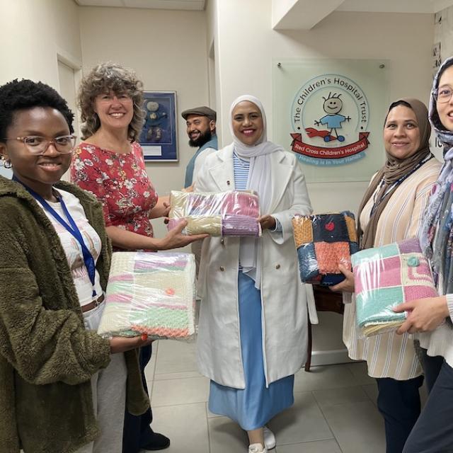 Woman hands parcel over to a representative while her colleagues look on
