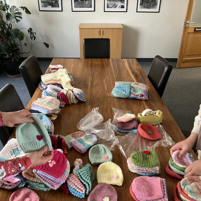 A woman packing knitted beanies neatly into a packet