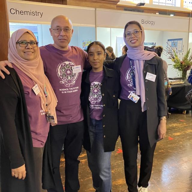 Four chemistry department staff members pose in front of the chemistry exhibition.
