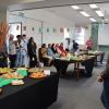 A room filled with people on the sides and tables filled with treats from different African countries.
